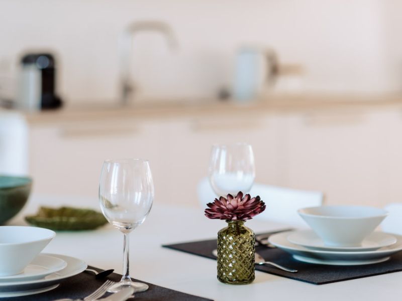 Gedeckter Esstisch mit Weingläsern, Tellern und dekorativer Vase in der Ferienwohnung Neuwied